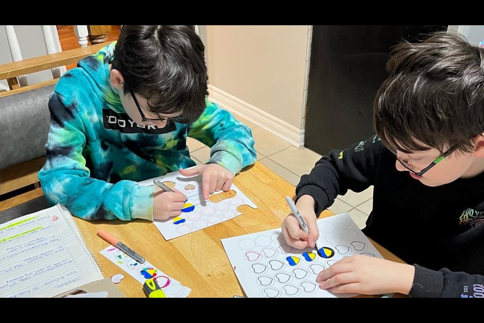 Twin brothers Jake and Owen Tubaro colour in paper hearts to make buttons. 