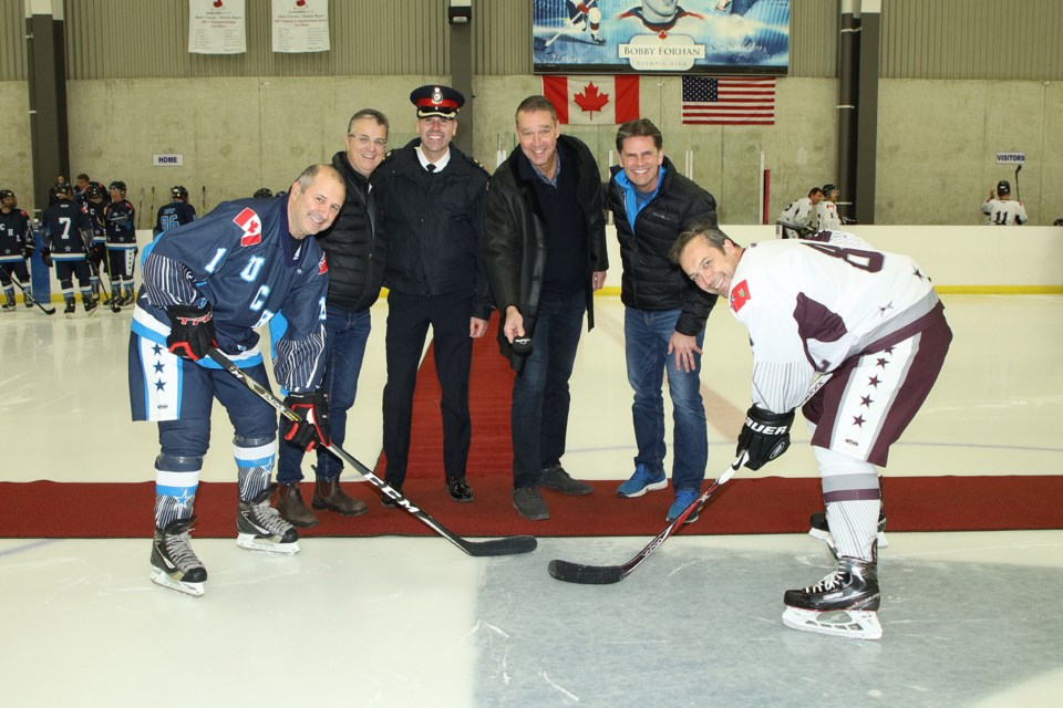 York Regional Police Chief Jim MacSween faces off against the captain of the Lexmark team for the ceremonial puck drop for the Scoring Goals for Community charity game in support of the United Way Saturday. Behind them are Dino Basso from York Region, YRP Deputy Chief Paolo Da Silva, Newmarket Mayor John Taylor, and Todd Greenwood from Lexmark.  Greg King for NewmarketToday