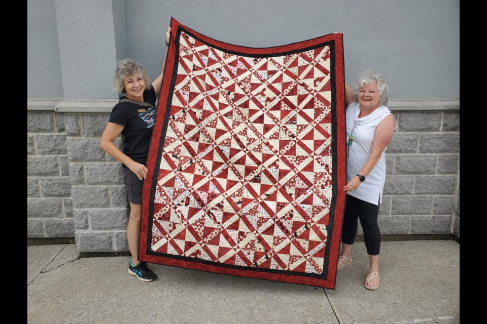 Members Paddy Honey and Naomi Babineau showcase a quilt from the Quilts of Valour program, which provides injured veterans with a special quilt of comfort 