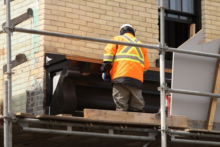A worker touches up the facade at 190 Main St. S., which is part of a group of properties formerly known as the Clock Tower project and now listed for sale separately. Greg King for NewmarketToday