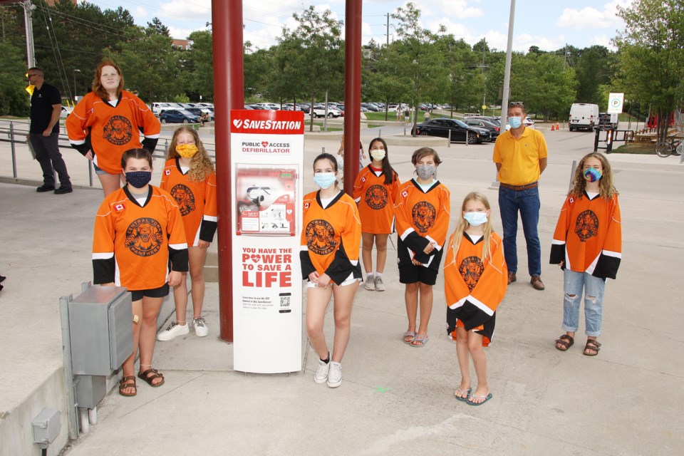 Members of the CYGHA Peewee Orange Crush team and Newmarket Mayor John Taylor at the unveiling of the SaveStation AED tower at Riverwalk Commons July 29.  Greg King for NewmarketToday