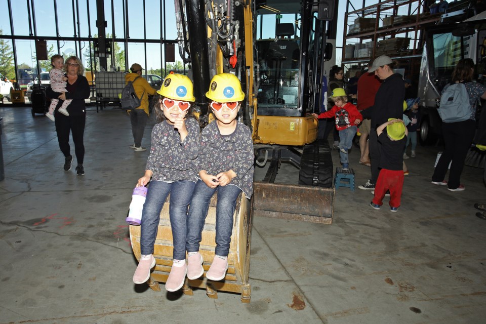 Elham and Elaheh Mojood sit the bucket of an excavator at the Town of Newmarket's Touch a Truck event May 25 at its operations centre.  Greg King for NewmarketToday