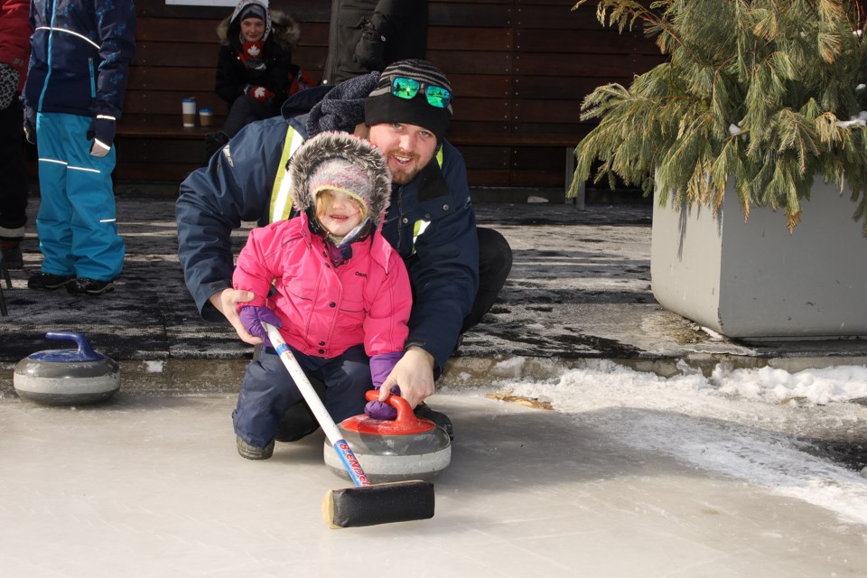 Craig Leamen helps his daughter Lorelei throw a curling stone the Town of Newmarket's Winterfest at Riverwalk Commons Feb. 15.  Greg King for NewmarketToday