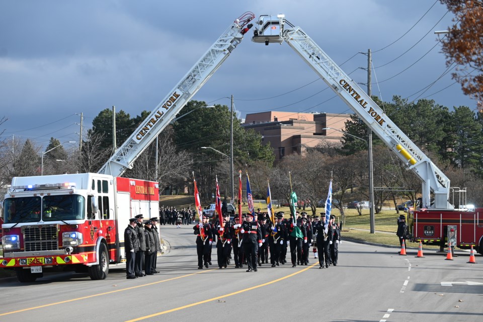 A funeral procession walks under an archway made by the Central York Fire Services on Eagle Street West for the funeral of fire chief Ian Laing Dec. 12. 