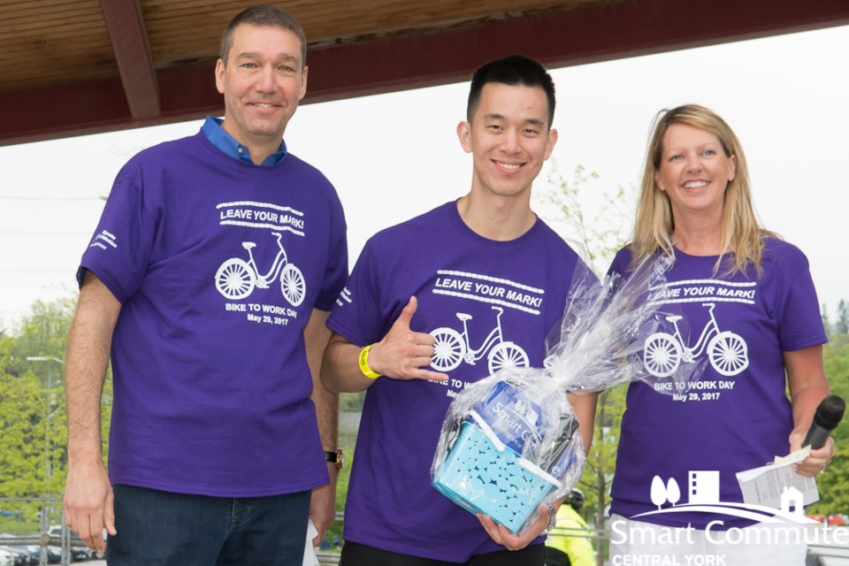 Joshua Wang, here with Mayor John Taylor and Councillor Jane Twinney, has won a prize two years in a row for cycling 38 km to attend Bike to Work Day at Riverwalk Commons. Supplied photo/Smart Commute