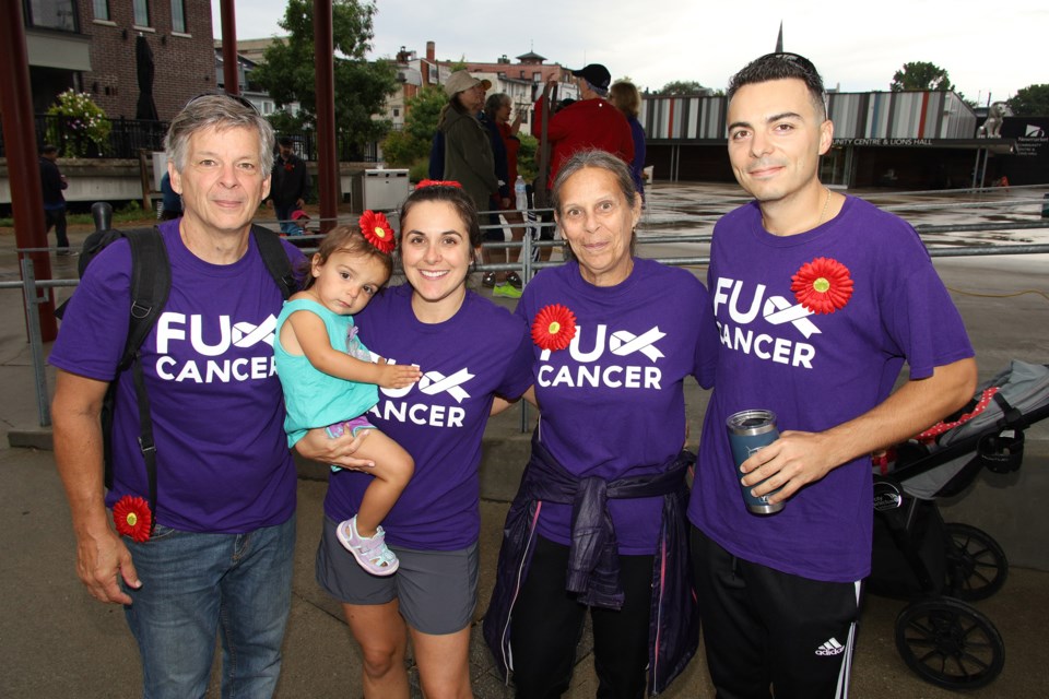 Don Neri, Sophia Dupont, Christine Dupont, Debbie Roccia, and Rob Dupont wear the red gerbera daisies that symbolize the battle against multiple myeloma at Newmarket's first fundraising walk/run Sunday at Riverwalk Commons.  Greg King for NewmarketToday
