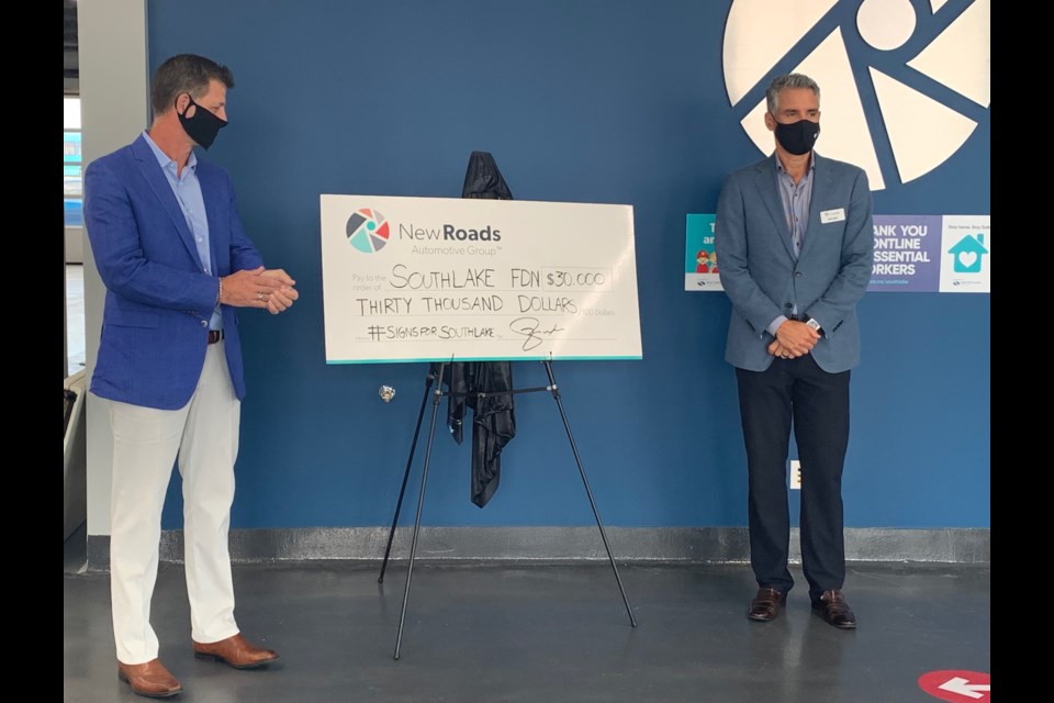 Chris Neal, co-owner of Neal Brothers Food (left), and Michal Croxon, president and CEO of NewRoads Automotive Group, present the proceeds of the Signs for Southlake COVID-19 initiative on Sept. 2. Debora Kelly/NewmarketToday