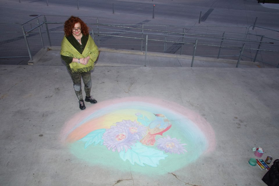 Newmarket artist Kim Egan stands by her latest work of chalk art at Riverwalk Commons.  Greg King for NewmarketToday