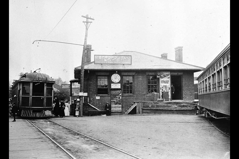 Passengers board the train at the Metropolitan Station, which has posters for the Toronto Exhibition and Newmarket Fair.