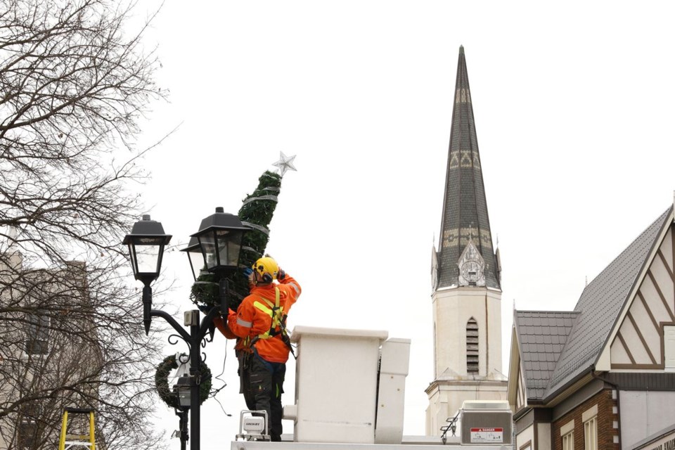 A worker puts up a holiday decoration in downtown Newmarket. 
