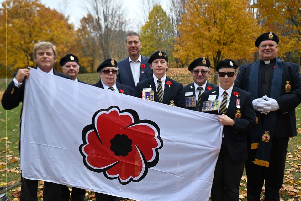 Dignitaries and members of the Newmarket branch of the Royal Canadian Legion hold up a poppy flag at Peace park Oct. 27. From left, Deputy Mayor Tom Vegh, past president Wayne Hooey,  zone secretary Diane Scaturchio, Newmarket Mayor John Taylor,  Newmarket legion branch vice-president Linda Hautala, zone commander Bruno Scaturchio, Newmarket branch president Crystal Cook, Newmarket branch chaplin Rev. Robert Royal. 