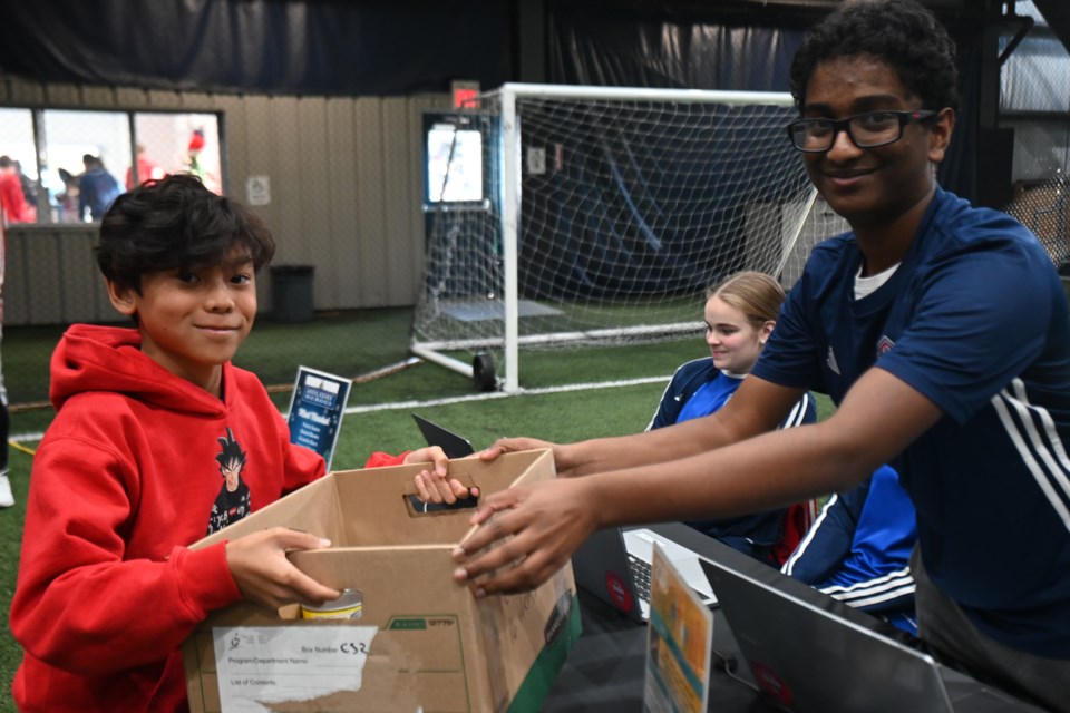 Jaden Mendoza hands off a food donation to Joshua Jacob at the York Regional Police's Newmarket Holiday Heroes kickoff Nov. 18. The event took place in partnership with the Newmarket Soccer Club at its facility in Newmarket.