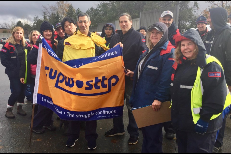 CUPW Newmarket Local 573 president Crystal DeLuca (left, holding banner) and vice-president Pat Culbert (far right) join members on the picket line at the Newmarket station on Mulock Drive this morning.
