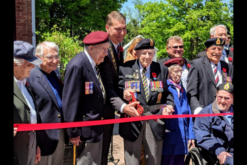 Mayor John Taylor, council members, local veterans and guests help cut the ribbon on opening day of the D-Day exhibit at Elman W. Campbell Museum.  Kim Champion/NewmarketToday
