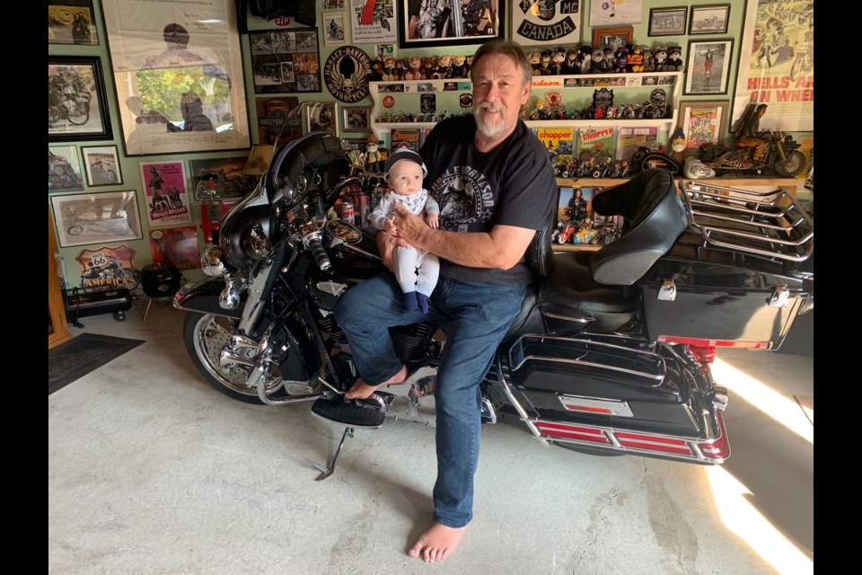 Dave Hoile and his grandson sit on one of his bikes in the man cave. 