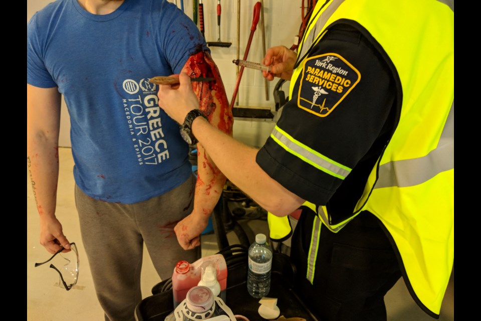 A volunteer gets fake blood reapplied before a training scenario begins.