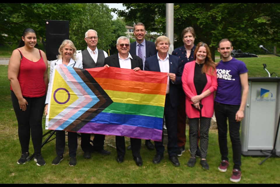 Newmarket council and Pride group representatives raise the progress Pride flag together, including (from left) York Pride's Brianne Evelyn,  council members Christina Bisanz, Victor Woodhouse, Bob Kwapis, John Taylor, Tom Vegh, Pflag's Damian Mellin, Councillor Kelly Broome, York Pride's Jacob Gall.