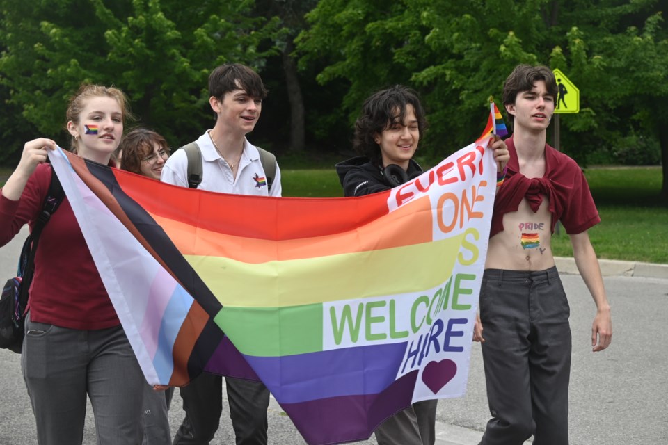 Students hold a progress Pride flag as they march for the walkout.