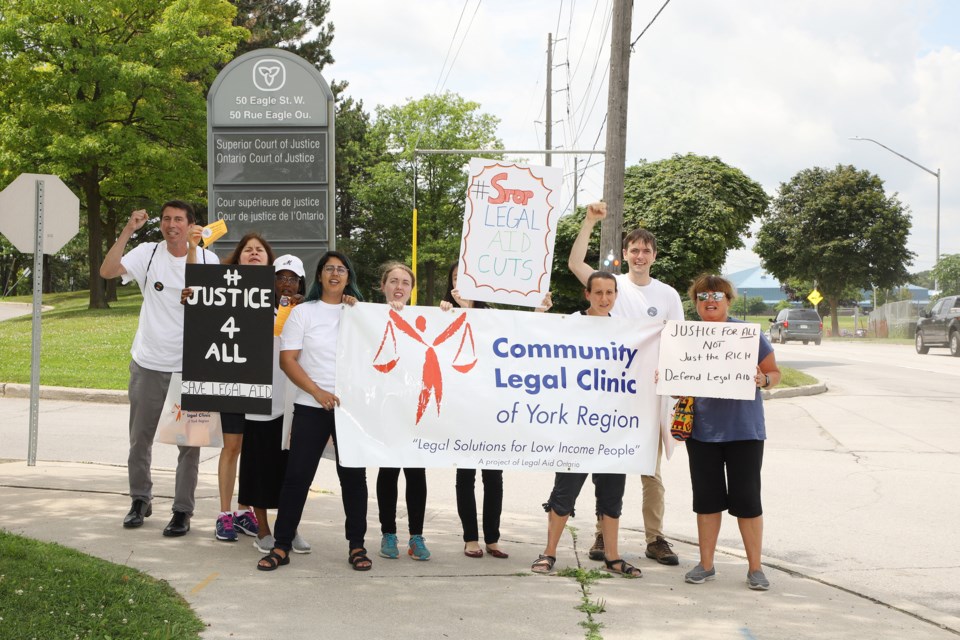 Community Legal Clinic of York Region staff marched with their banner at the Eagle Street entrance to the Newmarket courthouse parking lot yesterday.  Greg King for NewmarketToday