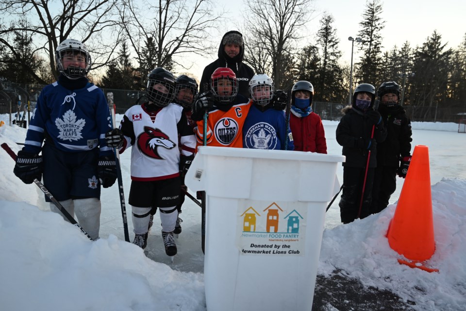 Kids gather around a food donation bin at the Lions Park Community Rink, run by Chris Howie (centre).