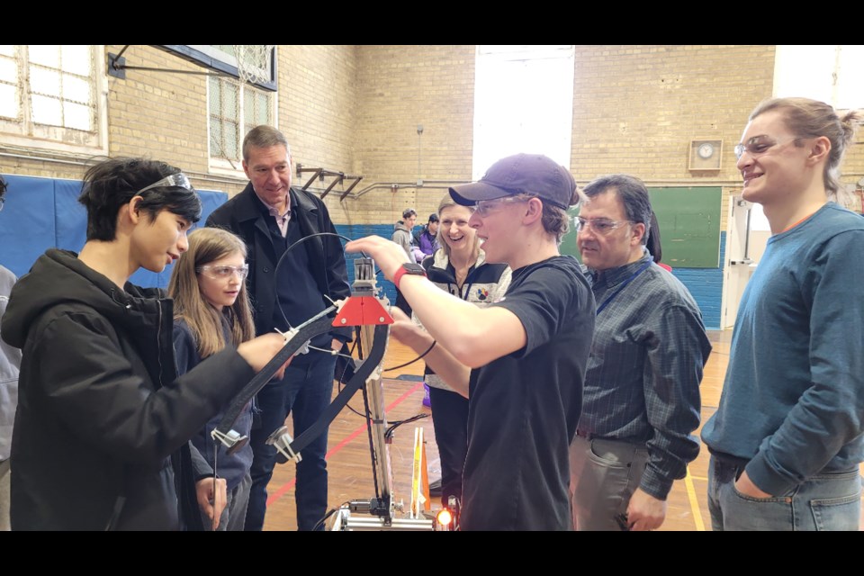 Newmarket Mayor John Taylor  watches the Newbotics team members make a repair to their robot at Pickering College last weekend as they prepare for the FIRST Robotics competition March 3 to 5 in Newmarket.  
