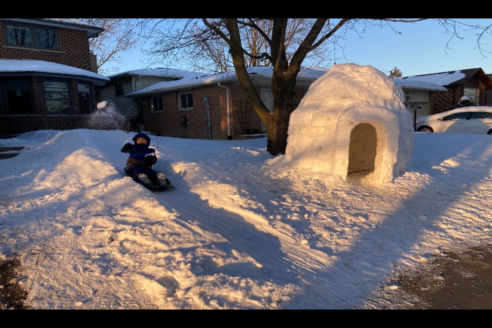 Kerr Chen's seven-year-old son plays on a snow slide built alongside their igloo. 