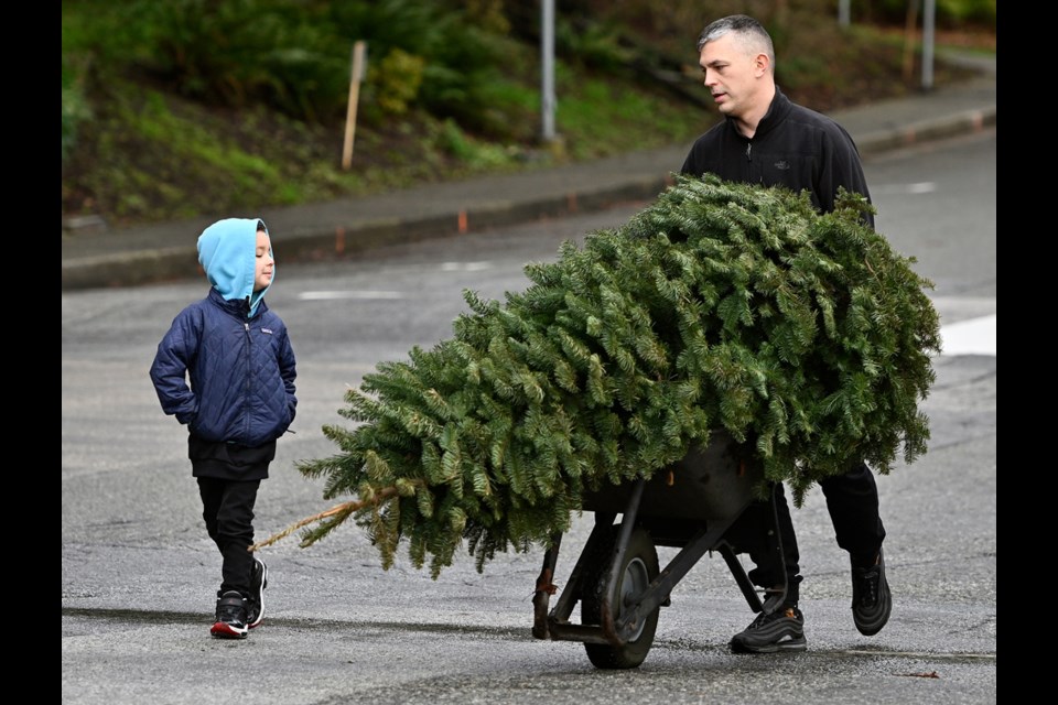 Ante Vukovic and 5-year-old Deon haul their tree in a wheelbarrow.