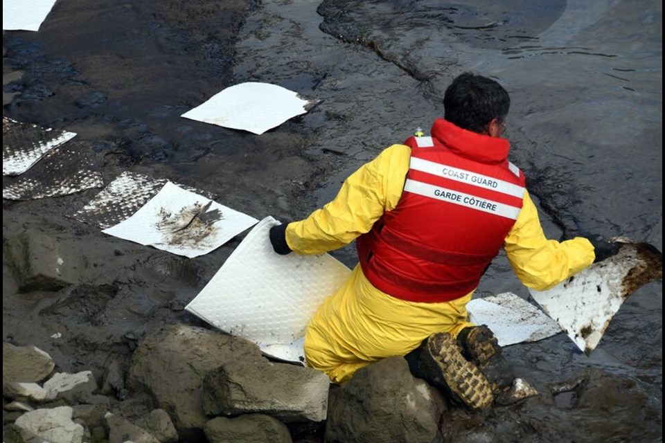 Cleanup time: A Coast Guard official works to clean up a small spill on New Westminster’s waterfront. photo Cornelia Naylor 