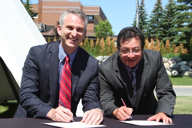 Bill Best, left, president of Cambrian College, and  Ron Sarazin, chair of the Circle for Indigenous Education at Cambrian College, sign the Indigenous Education Protocol during a ceremony at the Sacred Arbour on the main campus on June 20.