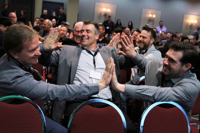 From left, Marty Holmberg, Jake Hughes and Andrew Marcotte, all from Technica Mining, were involved in a group exercise to demonstrate power and force by pushing on a “leader's” hands during speaker Michelle Ray's keynote address on April 16.