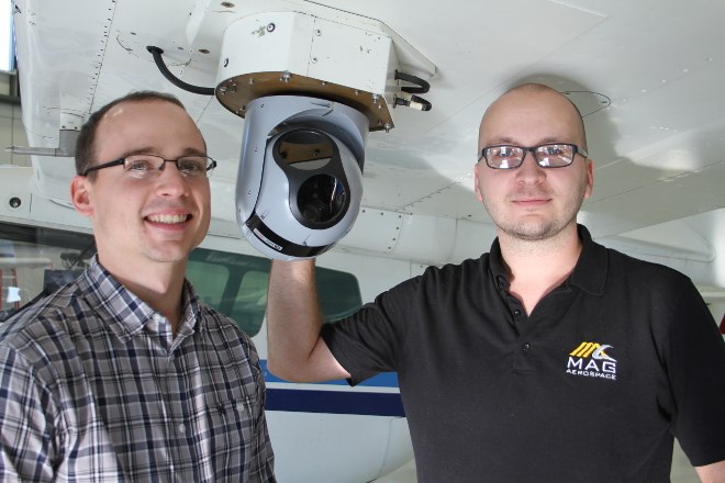 From left, Jason Fogg, VP of operations and Mike Ciezadlo, program manager, imagery, and both of Mag Aerospace, pose with a electronic optics and infrared sensor that is part of the sensor system Discovery Air Fire Services uses to spot and analyze blue-green algae blooms in waterways. Discovery Air is joining MAG Aerospace to offer more services.