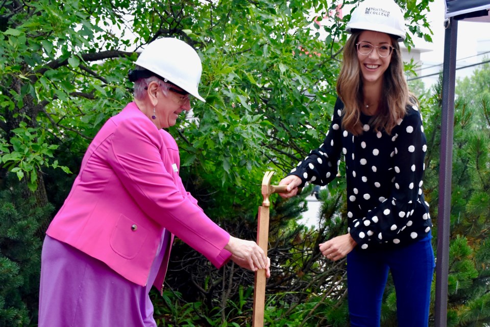 Northern College president and CEO Audrey Penner and Timmins Mayor Michelle Boileau hammer in a stake to mark the start of construction on the school's new downtown location. (Maija Hoggett/TimminsToday)