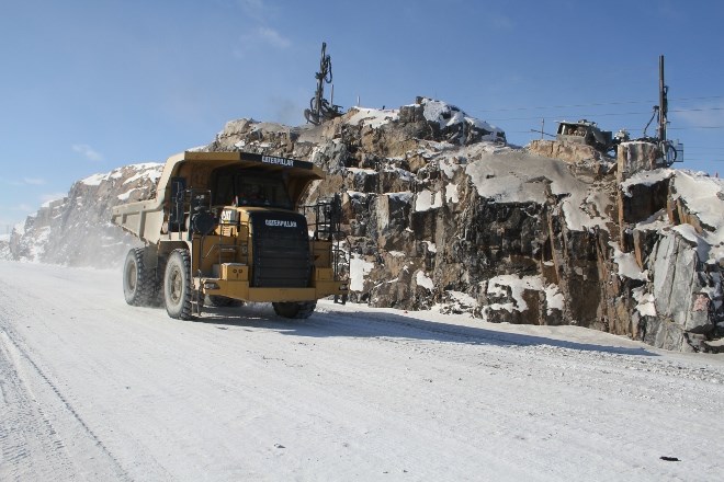 Drillers cut blasting holes into a rock cut along phase one of the Maley Drive extension as large haulers roll by. (Karen McKinley photo)