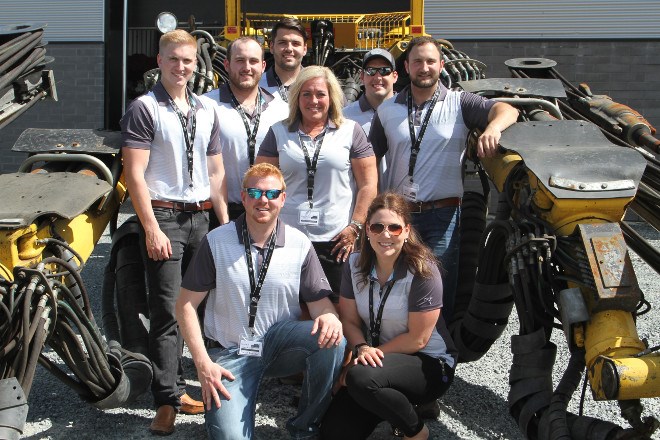 Back row, from left, business superintendent Brady Reilly, project coordinator Jordan Faggioni, summer student Mike Fabiili, project coordinator Scott Faulkner and project coordinator Johnny Pambianco; middle, executive assistant,reception and sponsorships Mary Anne Walsh; front row, from left, engineer Derek Laurikainen and human resources manager Cora DeMarco pose in front of one of the Atlas Copco 282 Jumbo drill at the Technica Mining headquarters on June 15. The company hosted its grand opening and open house, welcoming all to look at the new building and meet key staff members.