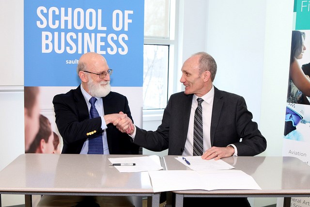 Dr. Stephen J. Havlovic (left), dean with the faculty of management at Laurentian University, and Colin Kirkwood, vice-president of academic and research at Sault College, sign a partnership agreement on March 21. (Supplied photo)