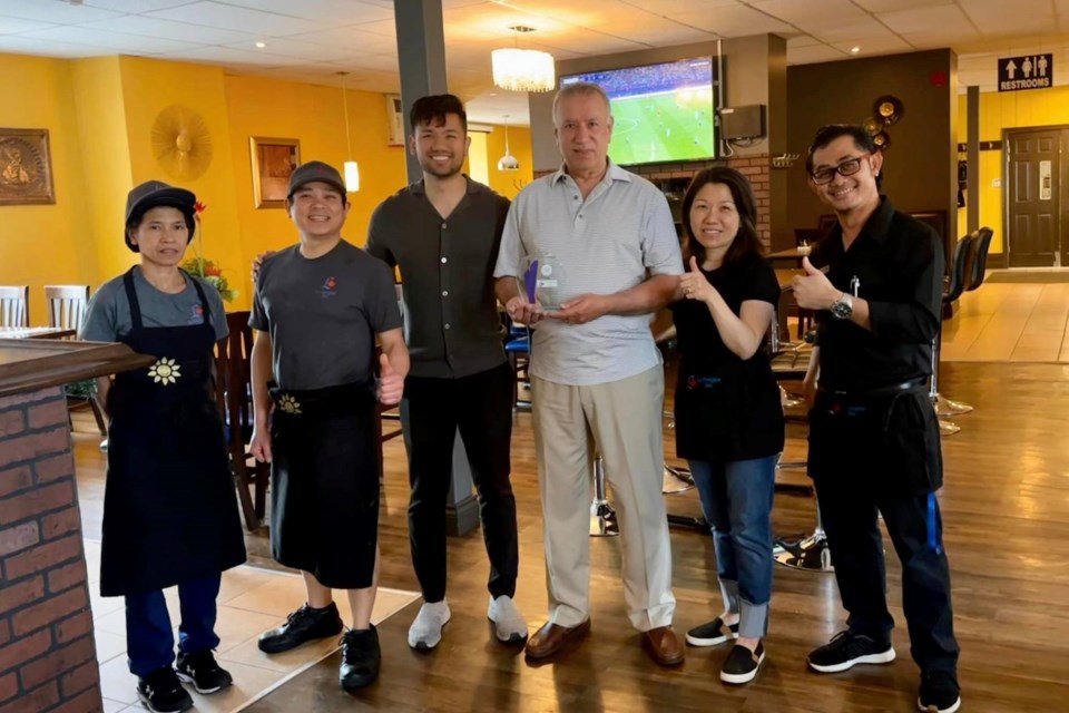 The owners and staff at Le Voyageur Inn hold their award for having the 'best Thai food in northeastern Ontario,' according to Luxe Life Magazine.