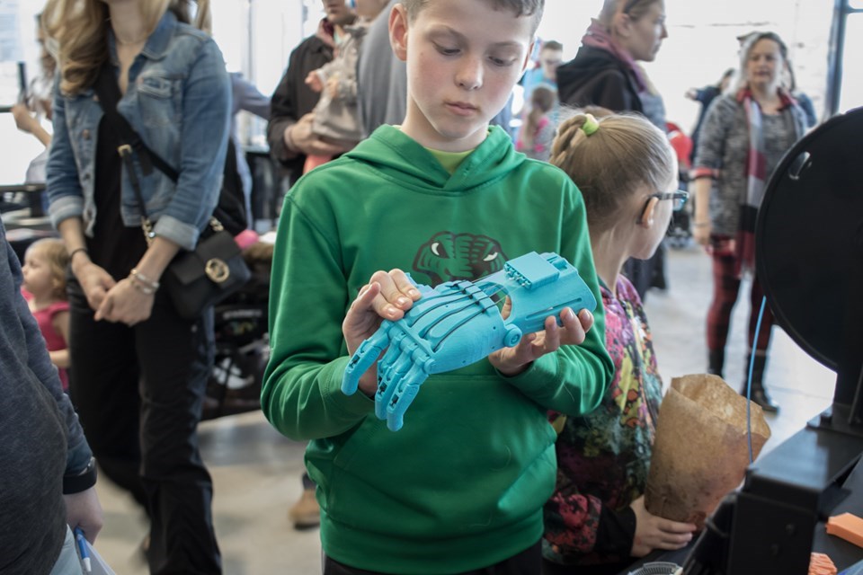 A young man examines a 3-D printed hand from the Maker North Inc. exhibitor booth at the Science Carnival on Saturday. Jeff Klassen