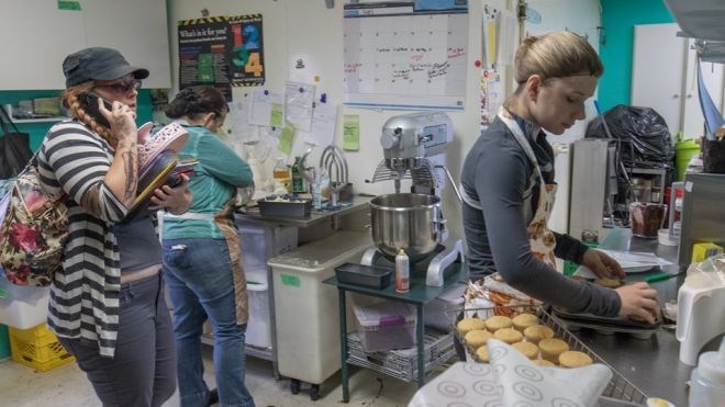With her hands full, Humphrey walks through the Radical Gardens kitchen while Jennifer Pye (left) makes muffins. Jeff Klassen photo