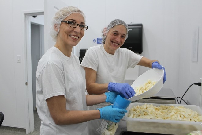 Melanie Soucy, left, and Georgia Richer weigh and pack bags of curds in the packing room. Some will be sold at the storefront, while others were reserved for an order from Smiths Markets.