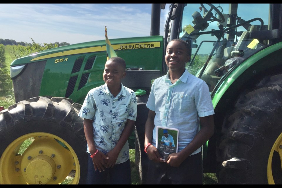 Devon McKenzie's two nephews pose beside Devon's favourite tractor at his memorial service this summer.