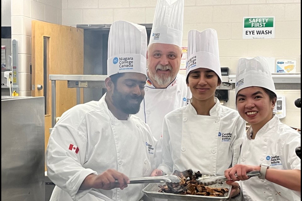 Chef Olaf Mertens with Niagara College students preparing meals in the Niagara College Benchmark kitchen. 