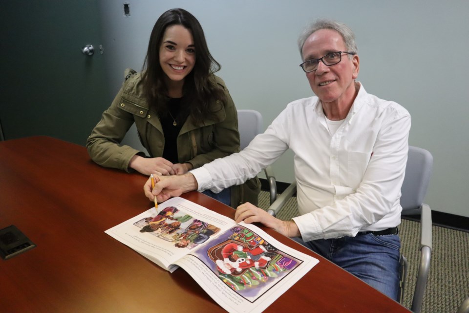 Illustrator Becca Marshall and author Al Huberts check out the final version of their new children's book 'River's Perfect Christmas'.