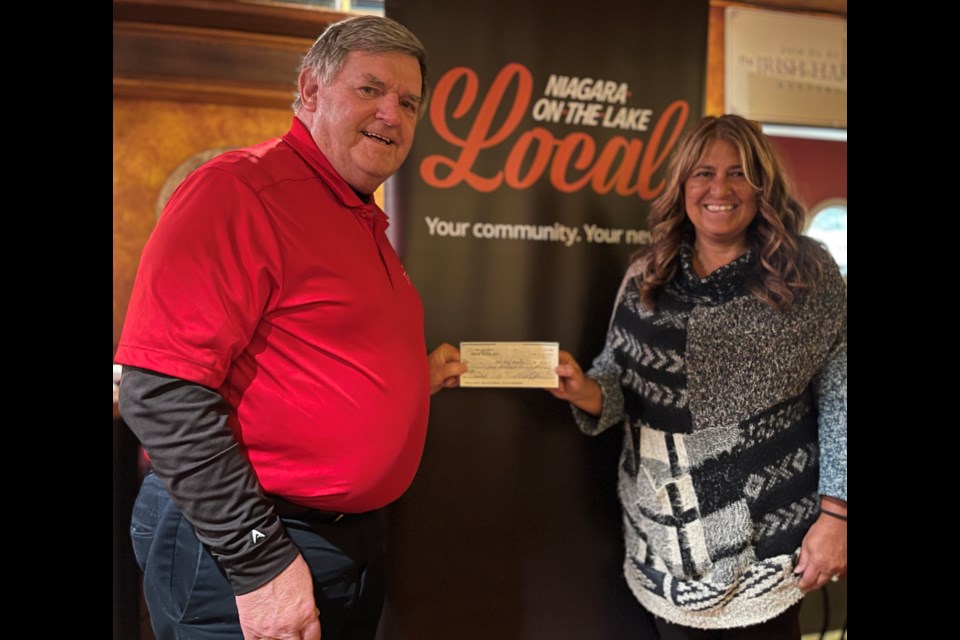 Jovie Joki of the Irish Harp presents bingo host and Red Roof Retreat board chair Ward Simpson with a cheque for $3,000.