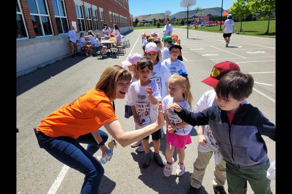 Teacher Michele Zoccoli high-fives the youngest students as they begin their walk around the track for the Rankin Cancer Run at Crossroads School.