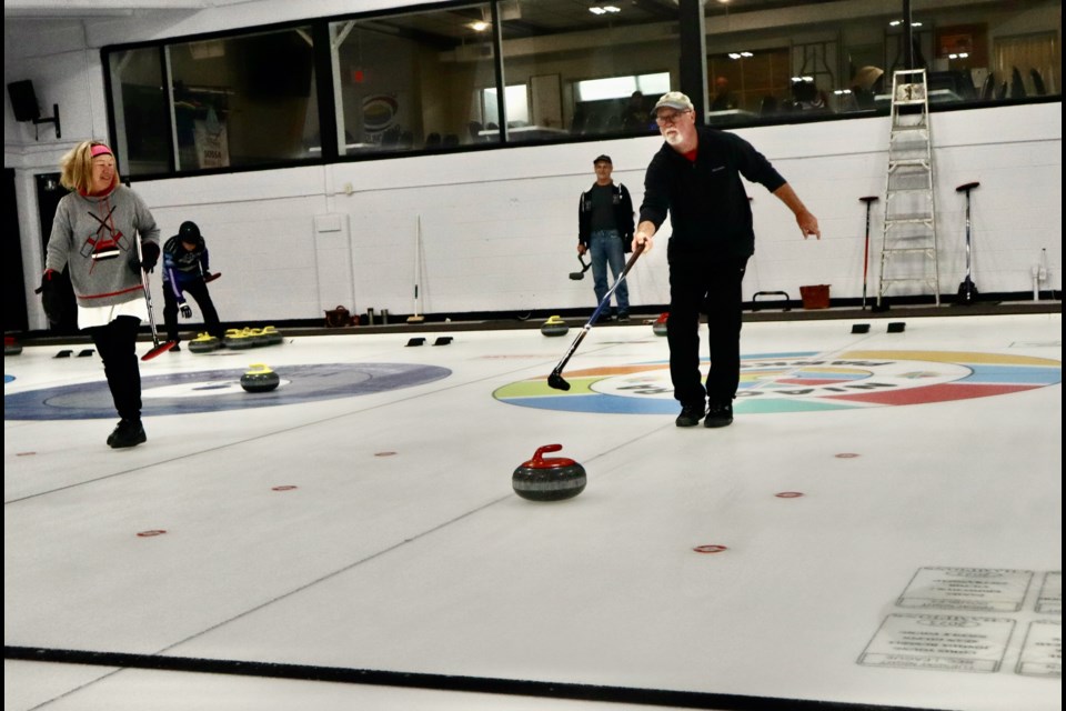 Janet Trinder watches as Randy Elliot of Niagara Falls uses a stick to curl