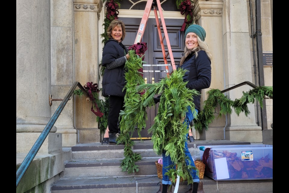 Brenda McArthur has taken on the task of decorating Queen Street for the  holidays — a natural for her, given that she loves Christmas in NOTL. She has a great team of helpers and volunteers to make it happen, she says. On the Court House steps Tuesday McArthur, with Emma Whyte, twists garland and bows around the railings.