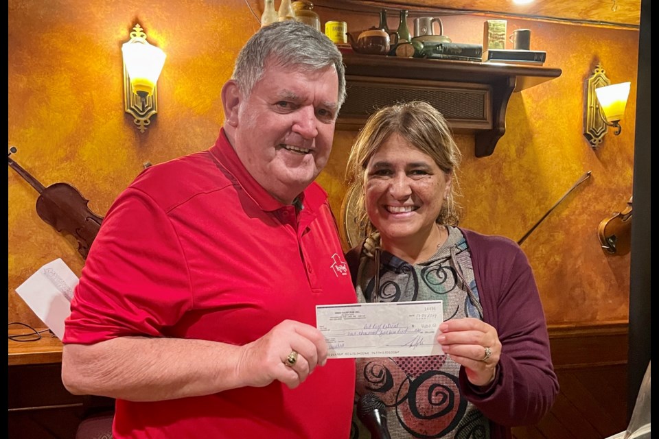 Jovie Joki hands Ward Simpson, board member of Red Roof Retreat, a cheque for $4,500 after the last bingo event. Half of that came from patrons, the other half from The Irish Harp.