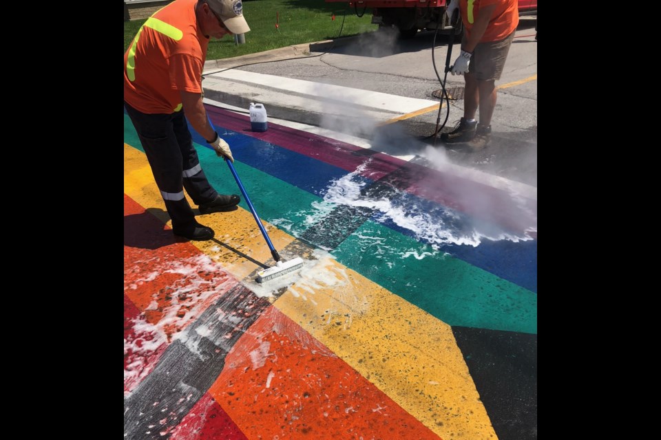 Town staff work to clean up the vandalism that marred the the Pride crosswalk earlier this week