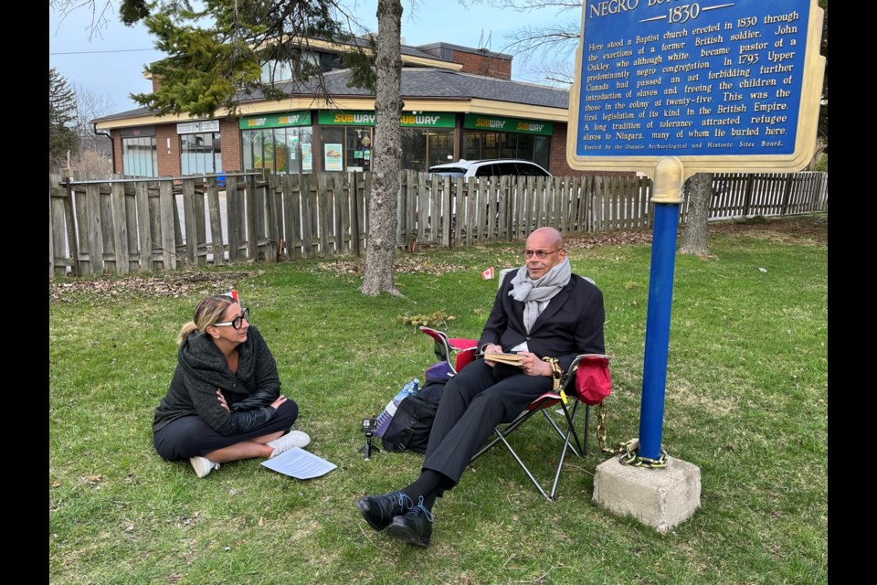Maria Mavridis sits with James Russell at the Negro Burial Ground, vowing to try to get five councillors to vote to fund the work Russell is asking for at the cemetery.