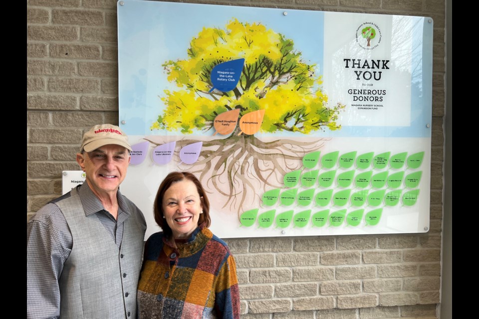 Alan and Diana Ash, donors to the nursery school, by the donor wall plaque. 
